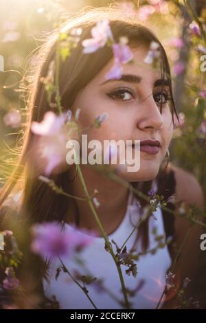 Porträt eines Teenagers, der zwischen den Blumen in der Natur lächelt Stockfoto