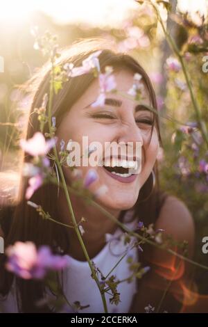 Portrait von jungen Mädchen lachen unter den lila Blumen in Natur Stockfoto