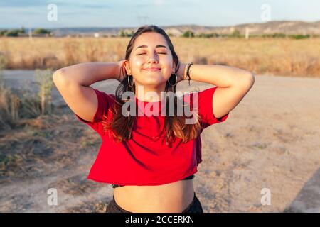 Glückliche Teenager berühren ihre Haare auf dem Land fühlen sich frei Stockfoto