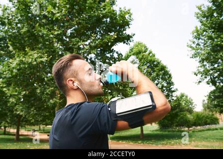 Mann trinkt Sportgetränk nach dem Training. Er ist in einem Outdoor-Park. Stockfoto