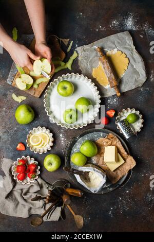 Küchentisch mit Produkten, Draufsicht. Mädchen schneidet den Appler. Draufsicht im Rahmen nur Hände. Stockfoto