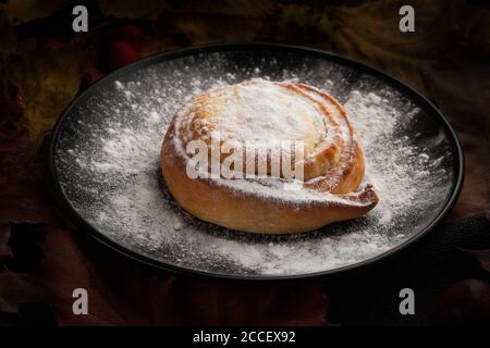 Käsekuchen bestreut mit Puderzucker auf einem schwarzen Teller Stockfoto