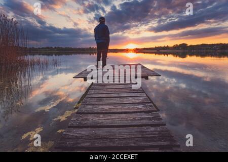 Europa, Deutschland, Bayern, Breitbrunn, Chiemsee, Chiemgau, Chiemsee, Mann steht auf dem Steg und blickt in den Sonnenuntergang, Stockfoto