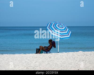 Frau am Strand unter dem Sonnenschirm sitzen Stockfotografie - Alamy