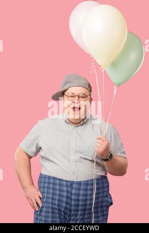 Fröhlicher lustiger emotionaler Mann in den 30er Jahren in grau gekleidet t-Shirt in karierte Hosen eingesteckt, überglücklich und begeistert Sein guter Witz mit Air bal Stockfoto
