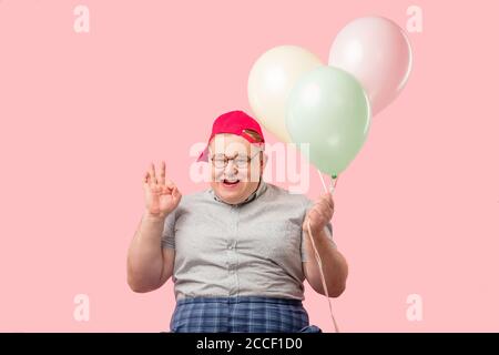 Fröhlicher lustiger emotionaler Mann in den 30er Jahren in grau gekleidet t-Shirt in karierte Hosen eingesteckt, überglücklich und begeistert Sein guter Witz mit Air bal Stockfoto
