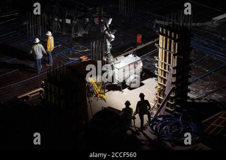 Austin, Texas, USA. Juli 2020. Betonbesatzungen arbeiten in der Parkgarage eines 53-stöckigen Gebäudes während eines nächtlichen Gefalles im Rainey Street District in der Innenstadt von Austin. Trotz dreistelliger Tagestemperaturen und steigender COVID-19-Zahlen bleiben die Bauprojekte in Texas unbehellig. Trotz umfangreicher Vorkehrungen sind die Baumannschaften weiterhin besonders gefährdet. Quelle: Bob Daemmrich/ZUMA Wire/Alamy Live News Stockfoto