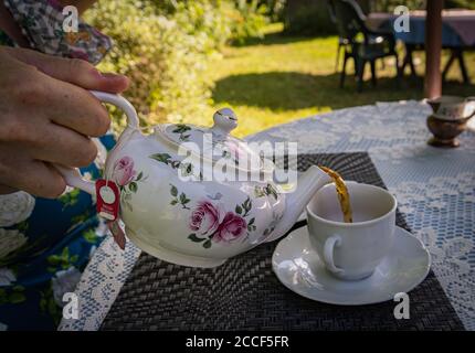 Eine wohlige Tasse Tee im Sommergarten gießen Stockfoto