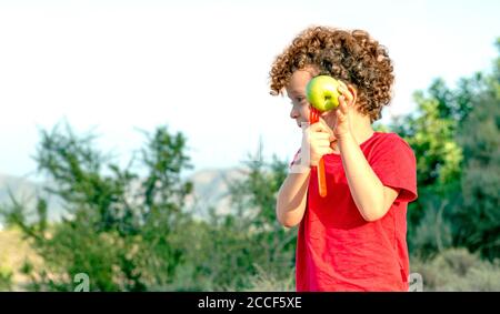 Junge spielt mit einem Apfel und einer Gabel in einem Landausflug, immer ein lustiges, glückliches und freundliches Bild Stockfoto