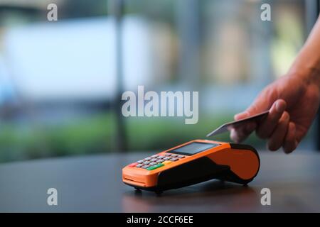 Nahaufnahme Menschen mit Kreditkarte, um über POS-Terminal auf dem Schalter zu bezahlen. Unschärfe Hintergrund Stockfoto