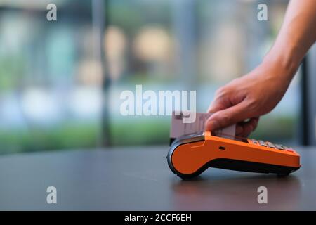Nahaufnahme Hände wischen die Kreditkarte auf POS-Terminal. Bunte Bokeh Hintergrund Stockfoto