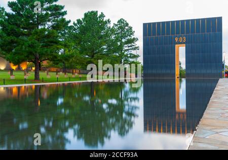 Oklahoma City USA - 9. September 2015; Oklahoma National Memorial Gate of Time und reflektierender Pool mit Feld von leeren Stühlen unter Bäumen auf der linken Seite. Stockfoto