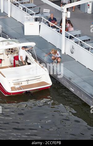 Ein Paar macht sich mit seinem Motorboot von der Außenseite eines Ausflugsboots auf den Main in Frankfurt auf den Weg. Stockfoto