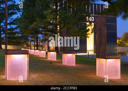 Oklahoma City USA - 9. September 2015; 9:03, Feld leerer Stühle mit Gate of Time und 9:03 im Hintergrund im Oklahoma National Memorial and Museum Stockfoto