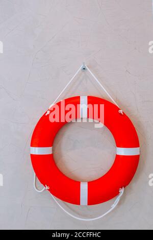 Rote Rettungsboje mit weißem Streifen an der weißen Wand hing, hatte Platz auf der linken Seite für kreative. Sicherheit auf dem Wasser Stockfoto