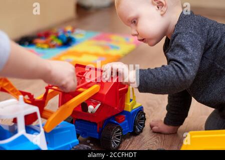 Mama zeigt ihrem kleinen Sohn, wie man mit einem Spielzeugtraktor spielt. Stockfoto