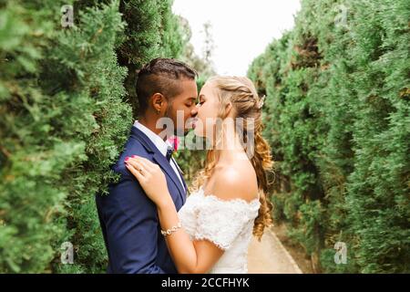 Hochzeit, Brautpaar, junge Erwachsene, Vielfalt, Liebe, Garten, Hecke, küssen Stockfoto