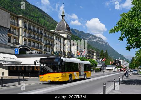 Postbus mit dem Victoria Jungfrau Grand Hotel im Hintergrund, Interlaken, Schweiz Stockfoto