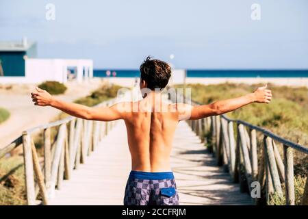 Junge kaukasische Mann offenen Armen genießen den Strand im Sommer Urlaub - Menschen vor dem Meer mit Blauer Himmel und Wasser im Hintergrund Stockfoto