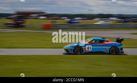 Eine Schwenkaufnahme eines blauen und orangenen Rennwagens, der eine Strecke fährt. Stockfoto