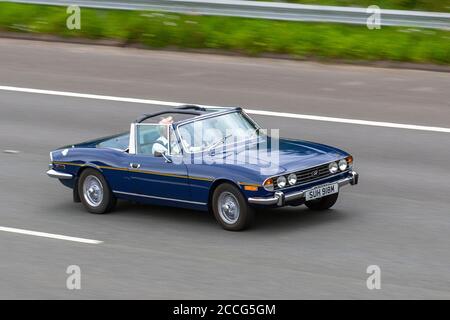 1974 70er Jahre Blue Triumph Stag Auto; Vehicular Traffic Moving Vehicles, Autos, die Fahrzeuge auf britischen Straßen fahren, Motoren, Autofahren auf dem Autobahnnetz M6, UK Stockfoto