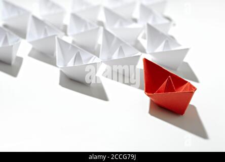 Leitbild. Rotes Origami-Schiff mit weißer Flotte, isoliert auf weißem Hintergrund. Stockfoto