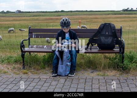 Boy liest auf Parkbank, Hiddensee Island Stockfoto