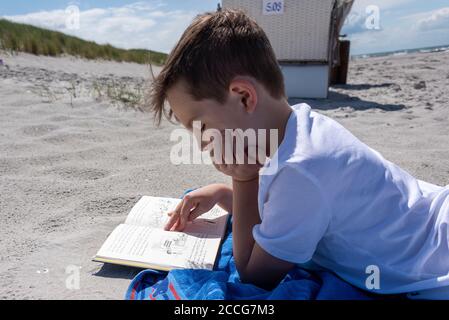 Junge liest am Strand Stockfoto