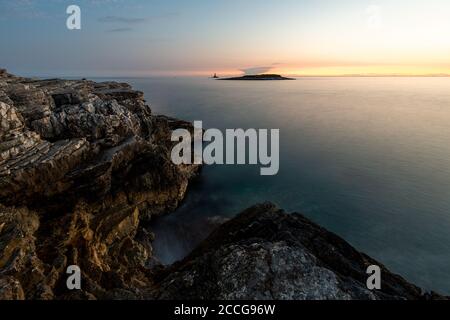 Abendlicht an den Ufern des Mittelmeers am Kap Kamenjak in Istrien, Kroatien. Zerklüftete Felsen, lange Exposition gegenüber glattem Wasser und einer kleinen isla Stockfoto