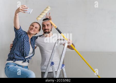 Eine Frau macht mit ihrem Freund ein Foto am Telefon. Sie halten eine Rolle Stockfoto