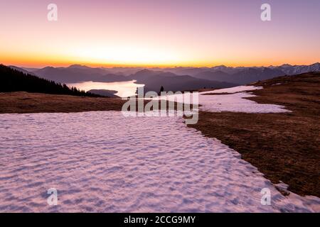Ein Schneefeld kurz vor Sonnenaufgang auf dem Simetsberg in den bayerischen Alpen des Estergebirges. Im Hintergrund der Walchensee und die Berge Stockfoto