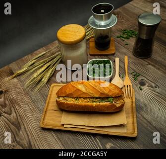 Snack in der Pause. Berühmte vietnamesische Küche ist Banh mi thit und schwarzen Kaffee, beliebte Street Food aus Brot mit Rohstoffen gefüllt: Schweinefleisch, Schinken, Pat Stockfoto