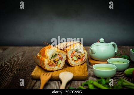 Snack in der Pause. Berühmte vietnamesische Küche ist Banh mi thit und heißer Tee, beliebte Street Food aus Brot gefüllt mit Rohstoff: Schweinefleisch, Schinken, Pastete, zB Stockfoto