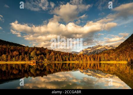 Das Bootshaus am Ferchensee im warmen Abendlicht der untergehenden Sonne im Frühsommer. Eine perfekte Reflexion unterstreicht die Wolkenstimmung und schön Stockfoto