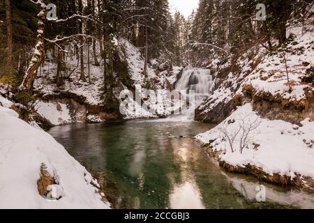 Wasserfall des Obernacher Kanals zwischen Wallgau und Walchensee In den bayerischen Voralpen im Winter mit Schnee Stockfoto