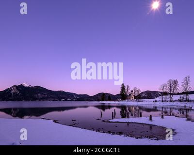 Mondschein über der Halbinsel Zwergern am Walchensee. Im Hintergrund der Jochberg und die Kapelle St. Margareth im Schnee Stockfoto