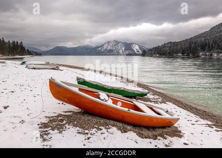 Wintereinbruch am Walchensee in den bayerischen Voralpen. Im Vordergrund ein Ruderboot und im Hintergrund der Herzogstand mit Schnee und Stockfoto