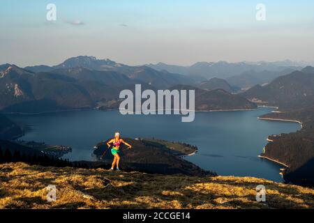 Trailrunnerin Katharina Kirschner läuft auf Simetsberg über dem Walchensee, im Hintergrund der See und das Estergebirge Stockfoto