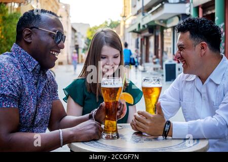Multirassische Gruppe von Freunden trinken und lachen auf der Straßenterrasse des Cafés. Freundschaftskonzept mit jungen multiethnischen Menschen genießen Zeit toge Stockfoto