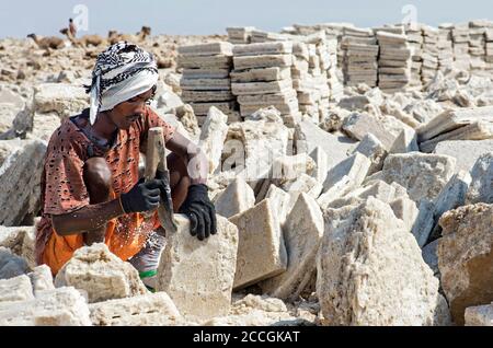 Der lokale Mann schneidet Salzblöcke in einem Salzbruch am Assale Salt Lake, Danakil Depression, Afar Region, Äthiopien Stockfoto