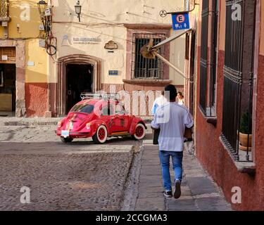 Red VW Käfer Wendepunkt in der Altstadt von San Miguel de Allende, mit Fußgänger zu Fuß vorbei Stockfoto