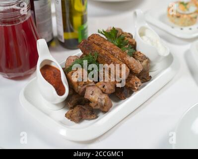 Gegrillter Kebab, Hähnchen- und Schweinespieße, rote und weiße Sauce auf einem Teller. Verschiedene Fleischsorten. Fleischgerichte. Bankett, Buffet-Menü Stockfoto