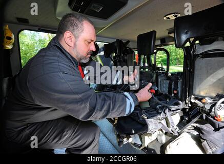 Feuerwehrmann, der Feuerlöschausrüstung für den Einsatz in der Kabine eines Feuerwehrmotors vorbereitet. Juni 2019. 2019.Kiewskaja Oblast, Ukraine Stockfoto