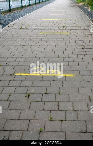 2 Meter gelbes Markierungsschild mit Pfeil auf Ziegelbad Führt zur Schule bereit für die Wiedereröffnung von Schulen mit sozialen Distanzierungsregeln im Sommer 2020 Stockfoto