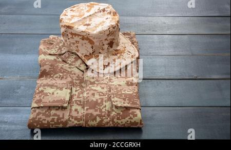 US-Armee-Mütze auf einem gefalteten Uniform, blaue Farbe Holzhintergrund. Militär Camouflage digitale Wüste Muster Shirt und Kopfbedeckung Stockfoto