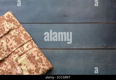 US Army acu Digital Desert Uniform Shirt auf blauem Holzhintergrund. Militär Camouflage digitale Wüste Muster gefaltet Hemd Detail, kopieren Raum, templa Stockfoto