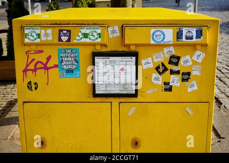 Öffentlicher gelber Briefkasten (deutsch: Briefkasten) aus Stahlplatte, teilweise mit Aufklebern bedeckt. Stockfoto