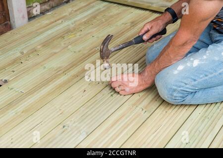 Nahaufnahme von Menschenhänden Hämmern einen Nagel zu machen Holzterrasse zu Hause für den Garten während des Schließens Stockfoto