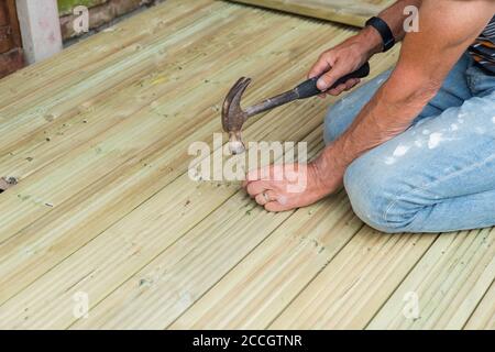 Nahaufnahme von Menschenhänden Hämmern einen Nagel zu machen Holzterrasse zu Hause für den Garten während des Schließens Stockfoto