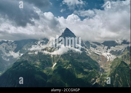 Scharfe Bergspitzen-Landschaft mit bewölktem Himmel, felsigen Bergketten und Gipfeln mit Gletschern und Schneefeldern. Blick auf die wilde Natur. Belalakaya, Dombay, Kaukasus Stockfoto